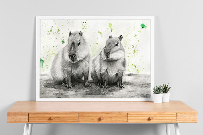 Fertige Zeichnung 2er Capybaras gerahmt auf einem Schreibtisch.