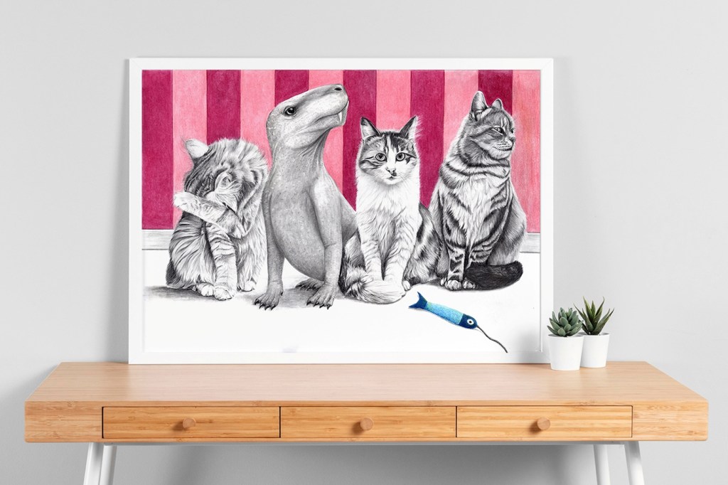 Bild 3er Katzen und eines Dinosauriers geramt auf einem Schreibtisch.